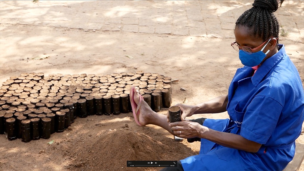 a woman wearing a mask and gloves is making a pile of logs.