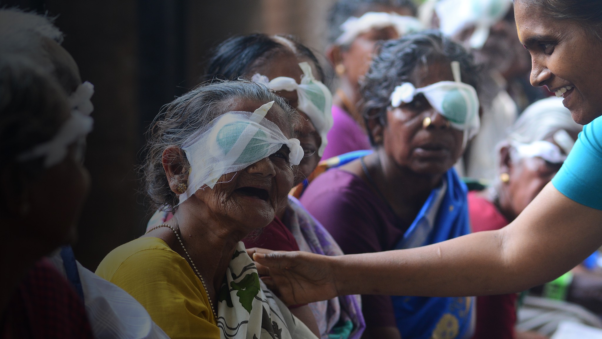 a woman is giving eye glasses to an elderly woman.