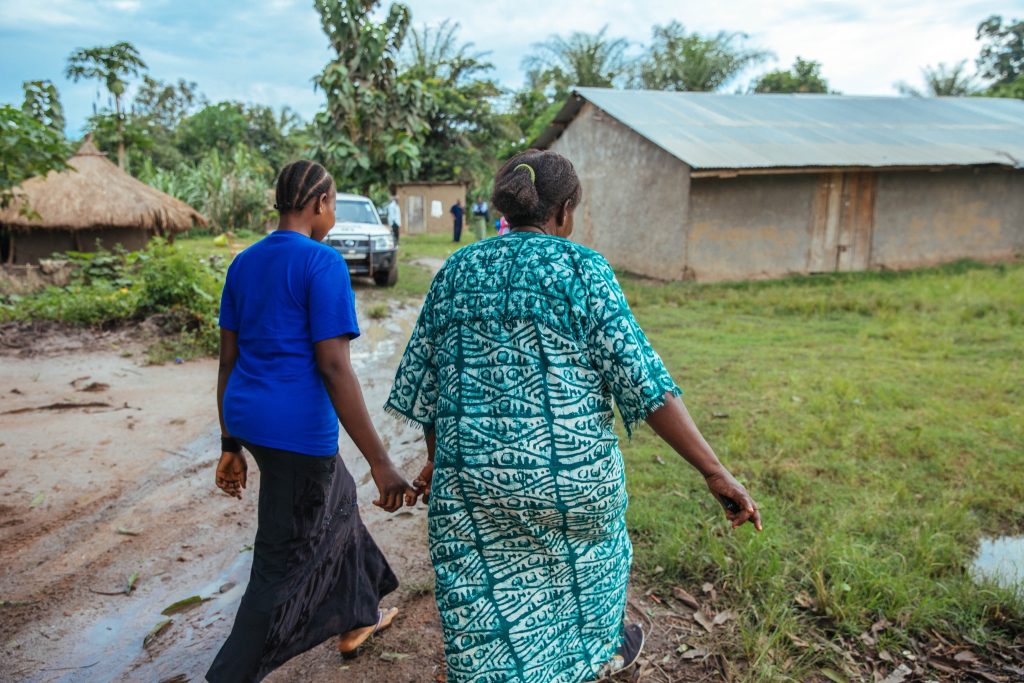 two women walking down a dirt road.
