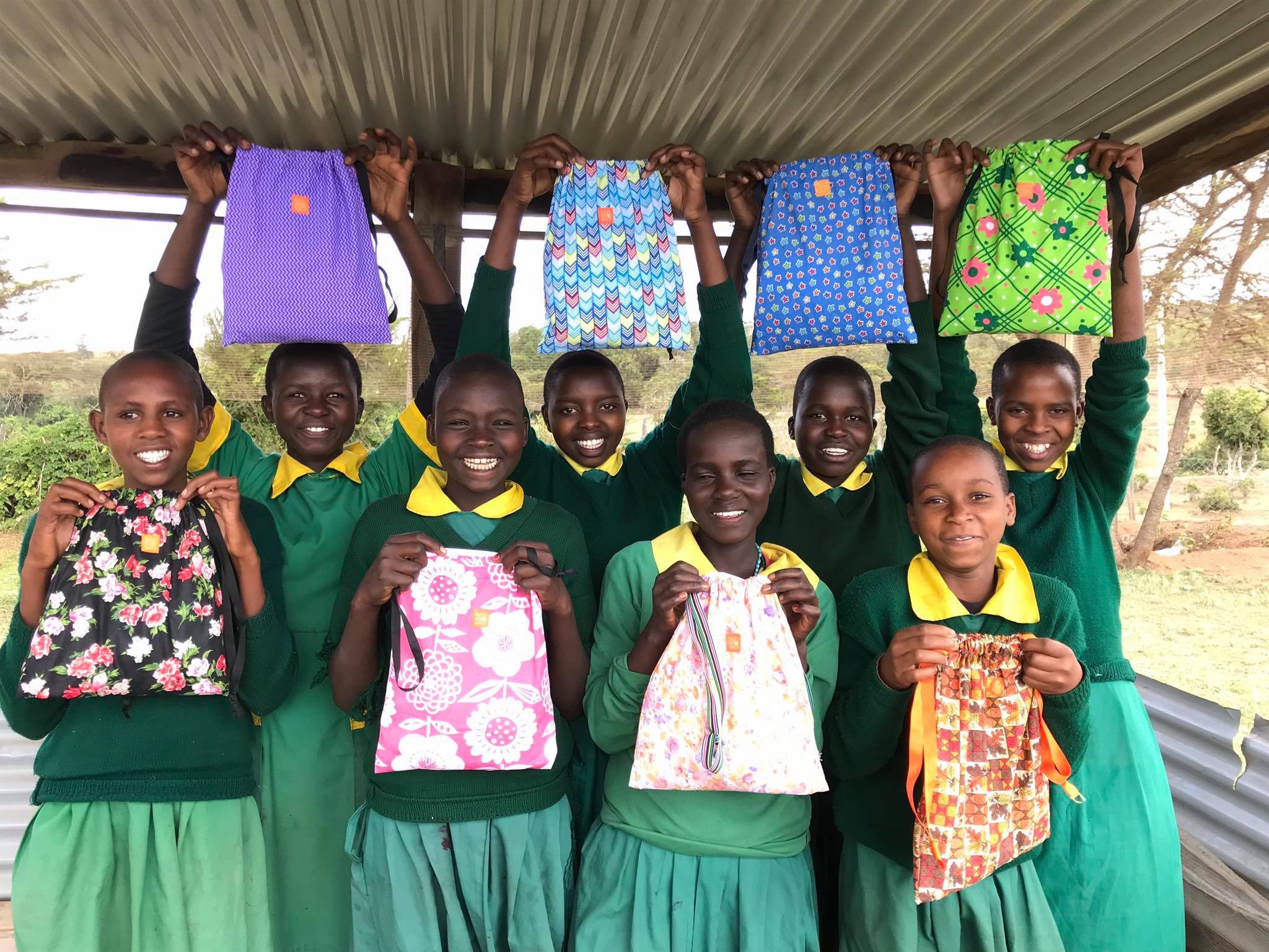 a group of girls in school uniforms holding backpacks.