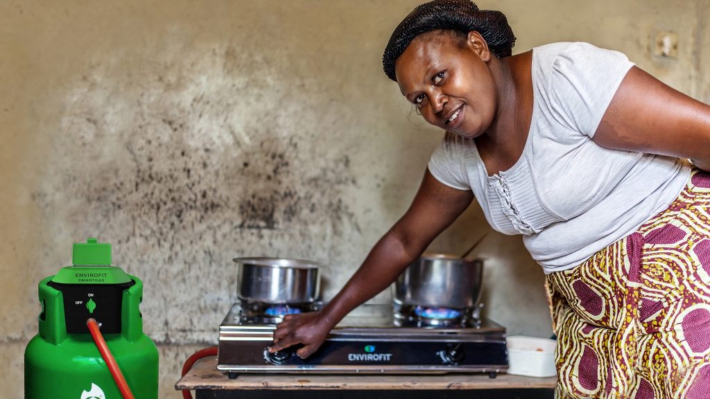 a woman standing next to a stove with a green gas cylinder.
