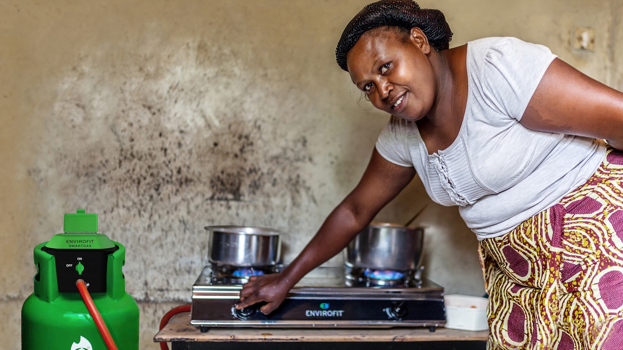 a woman standing next to a stove with a green gas cylinder.