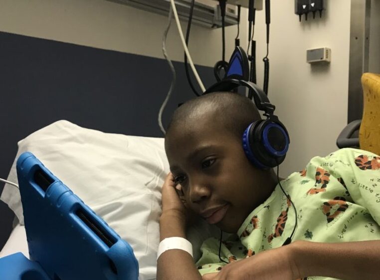 a boy in a hospital bed with headphones on.