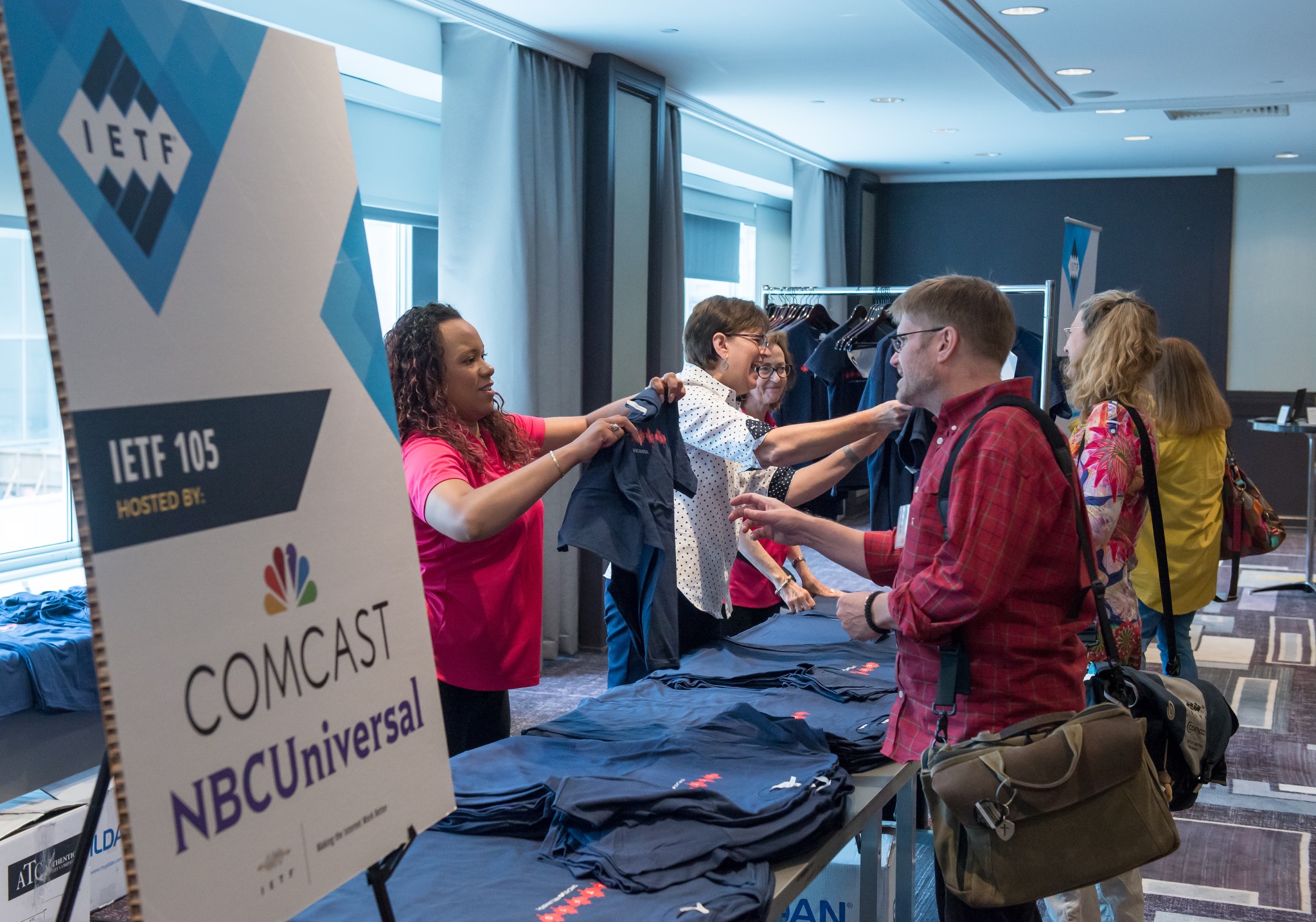 a group of people standing at a table with t - shirts.