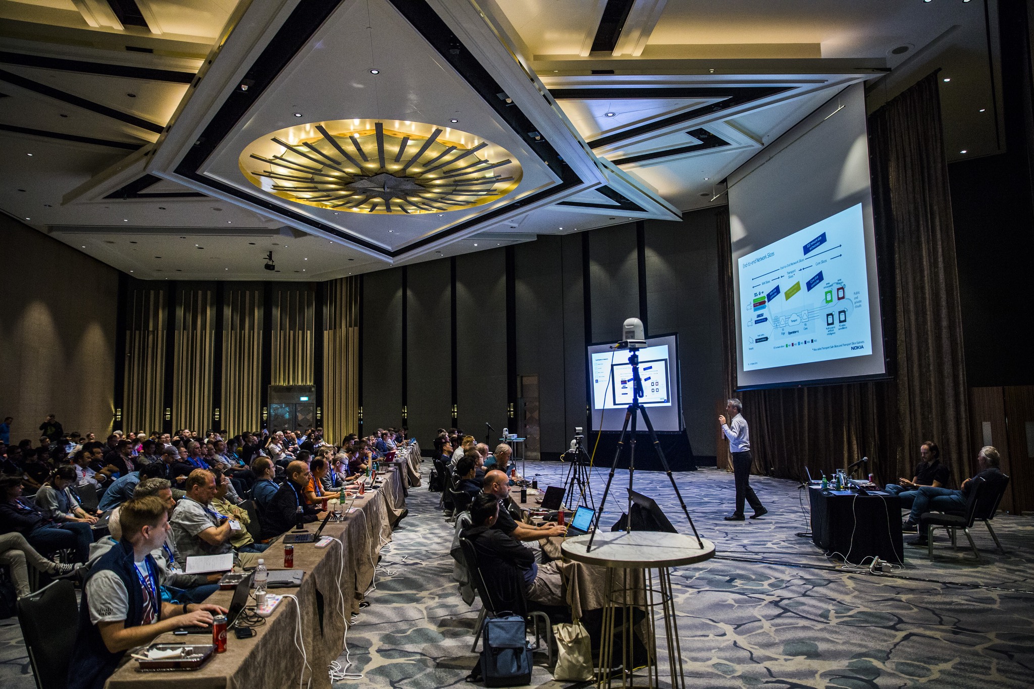 a large conference room with many people sitting at tables.