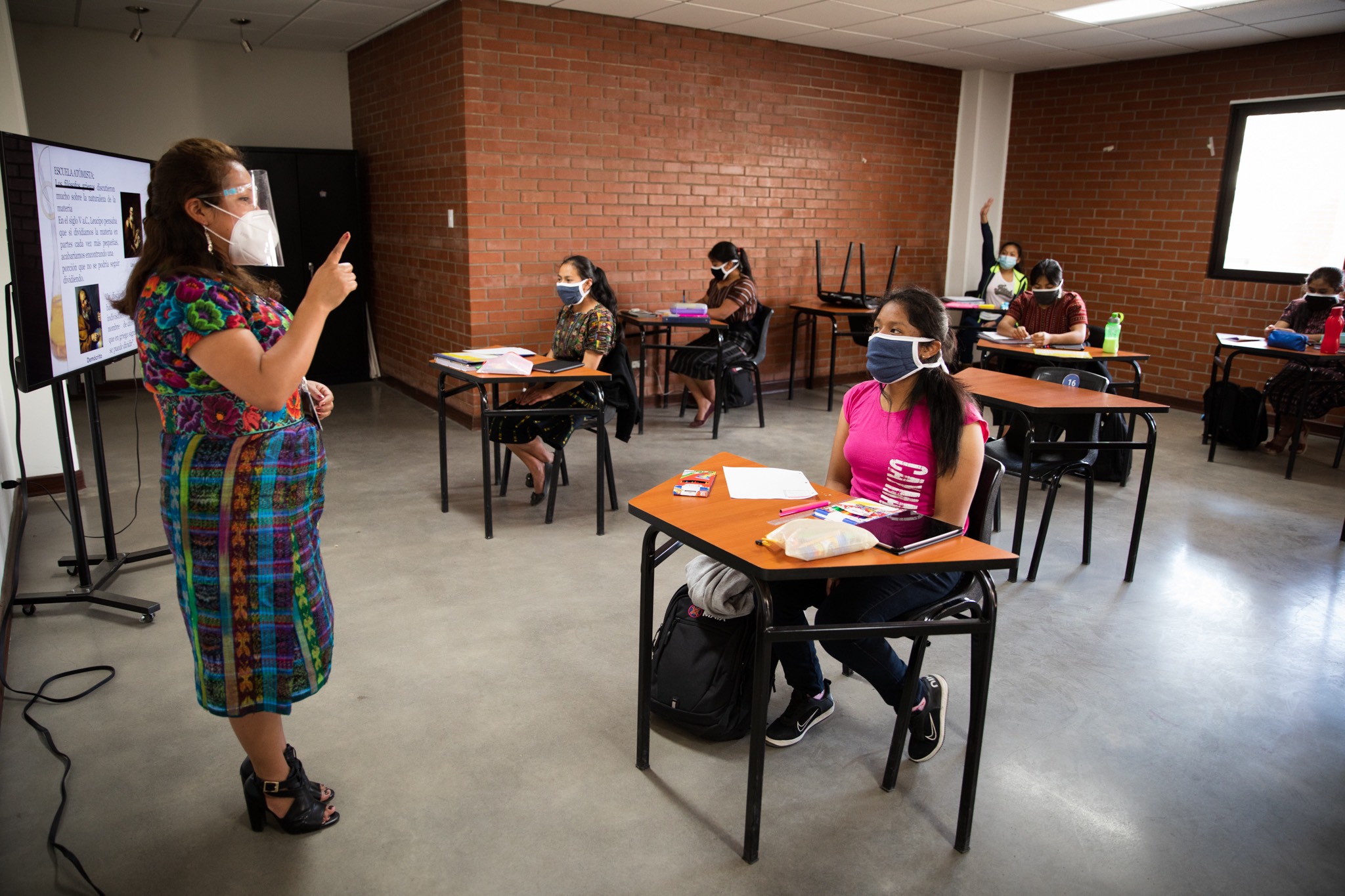 a woman teaches a class of students in a classroom.