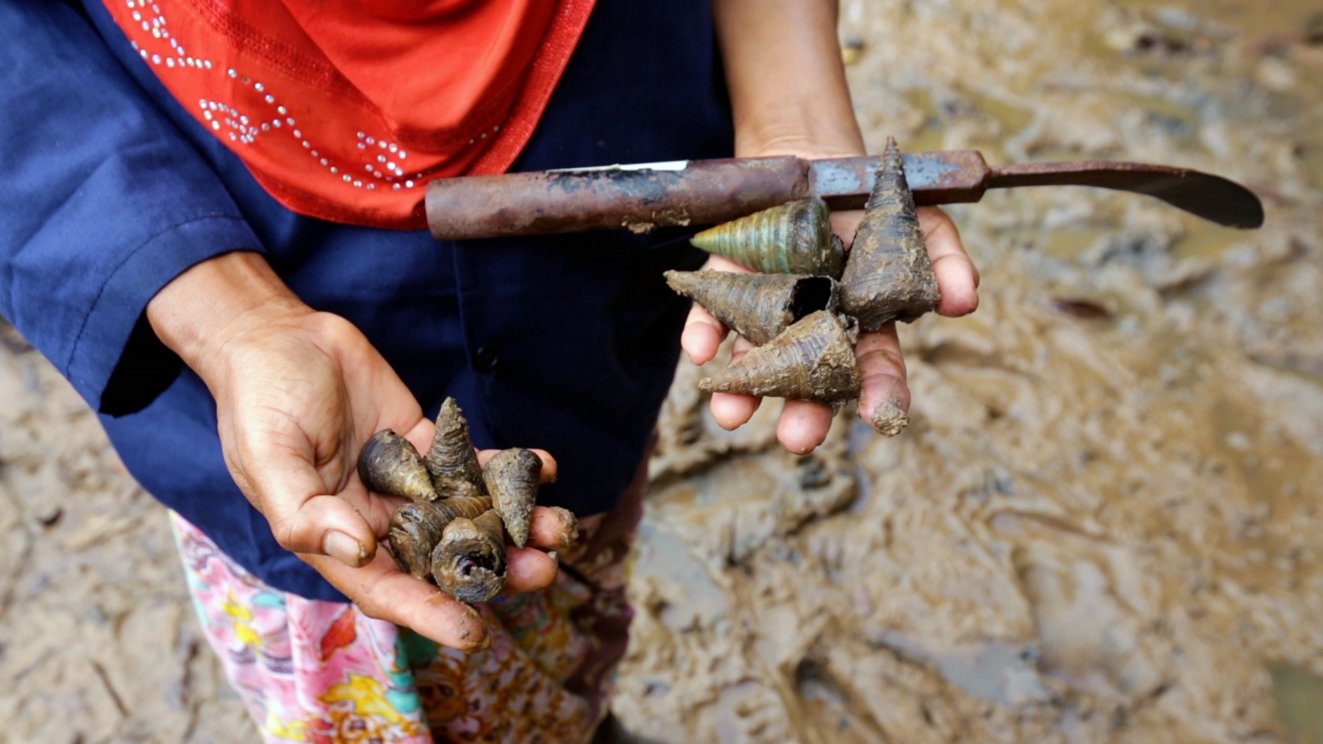 a woman is holding a shovel in the mud.
