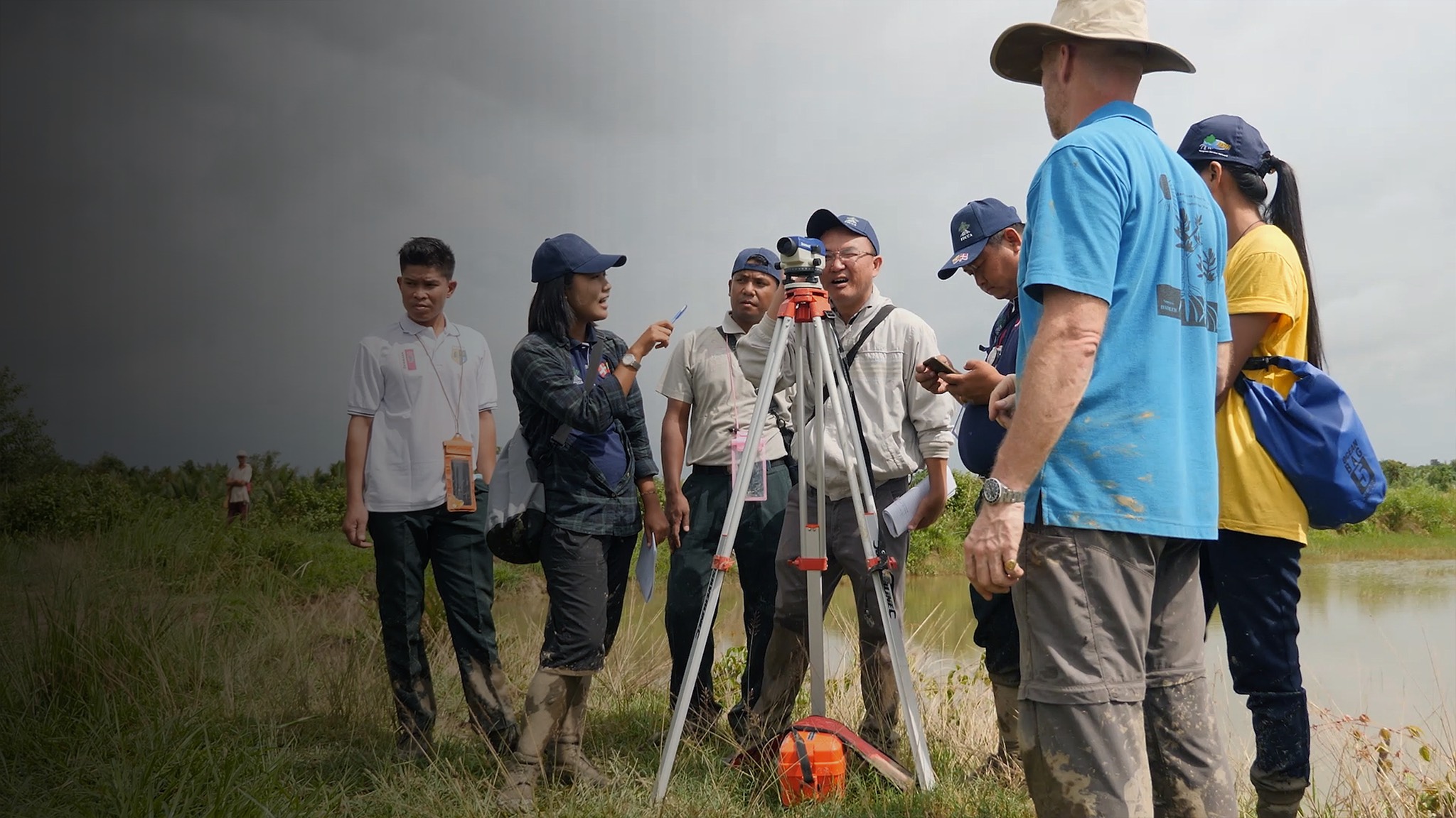 a group of people standing in a field with a surveyor.