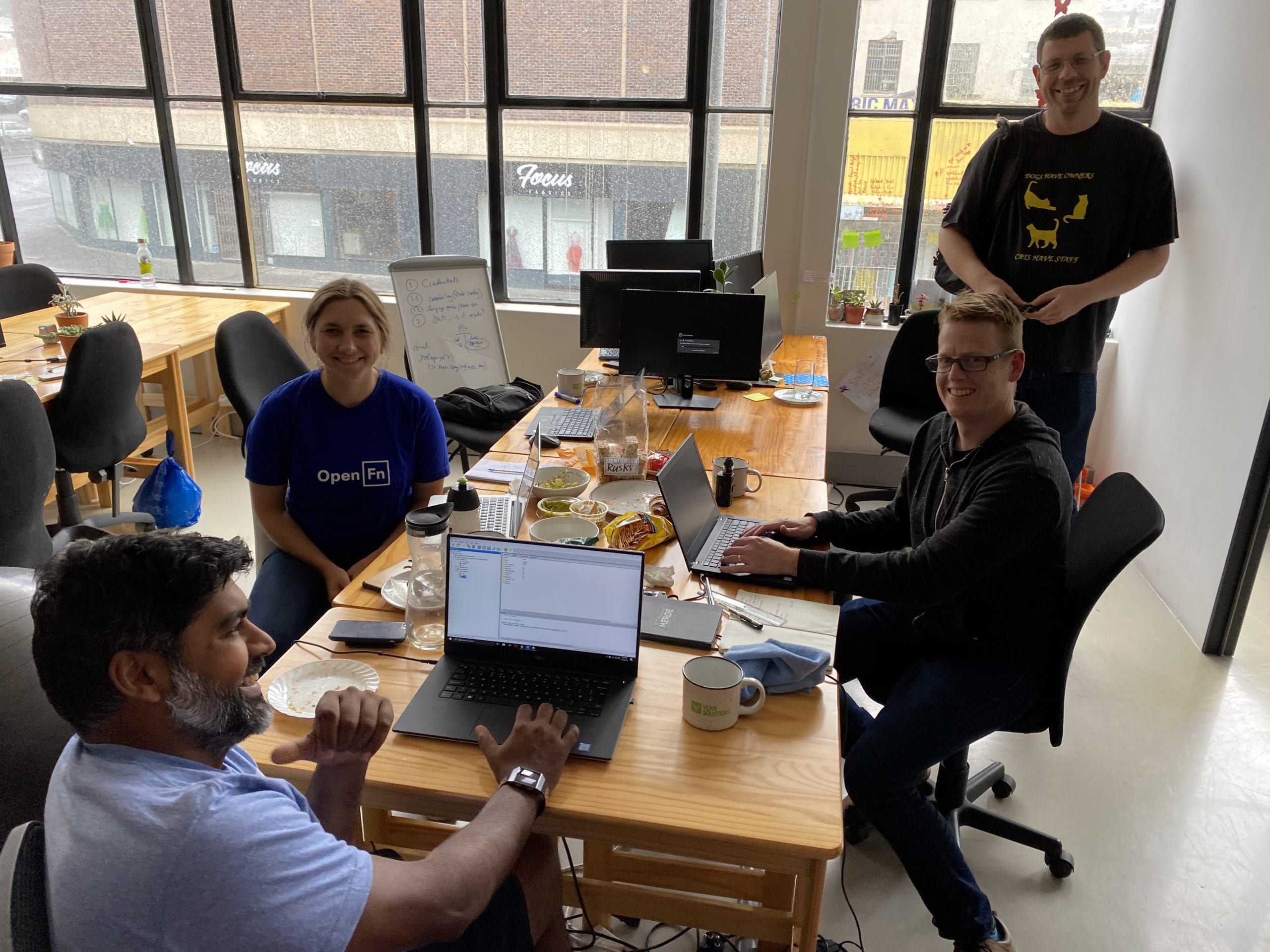 a group of people sitting around a table with laptops.