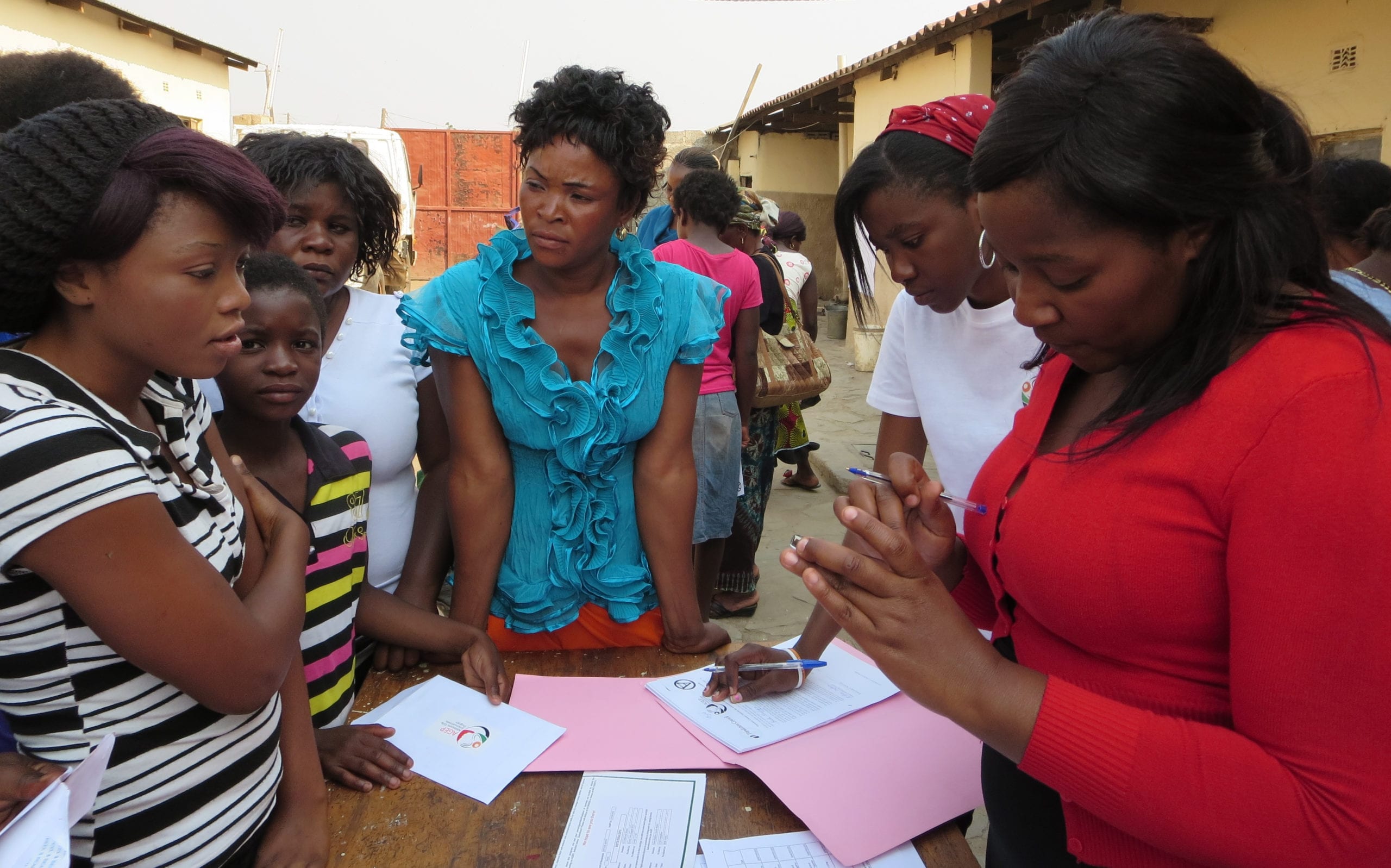 a group of people standing around a table with papers.