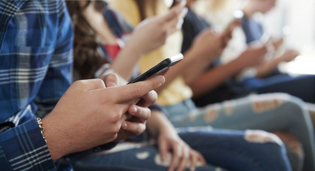 A row of people sitting and using their smartphones, with the logos of PIR and IWF visible in the top left corner of the image.