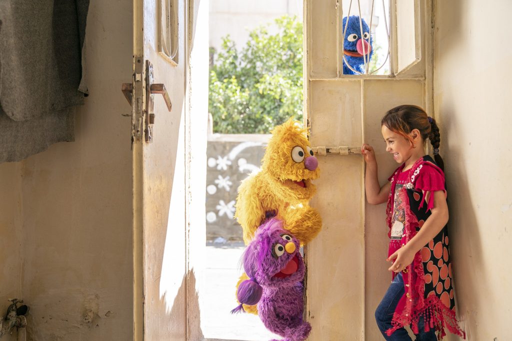 a girl is standing in front of a door with stuffed animals.
