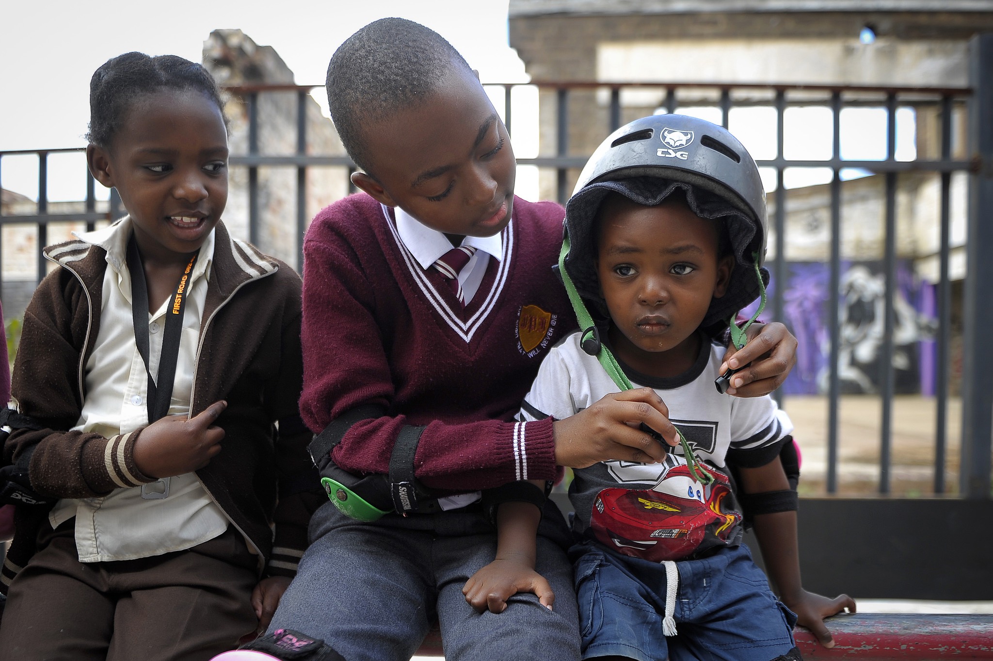 a group of children sitting on a bench with a helmet on.