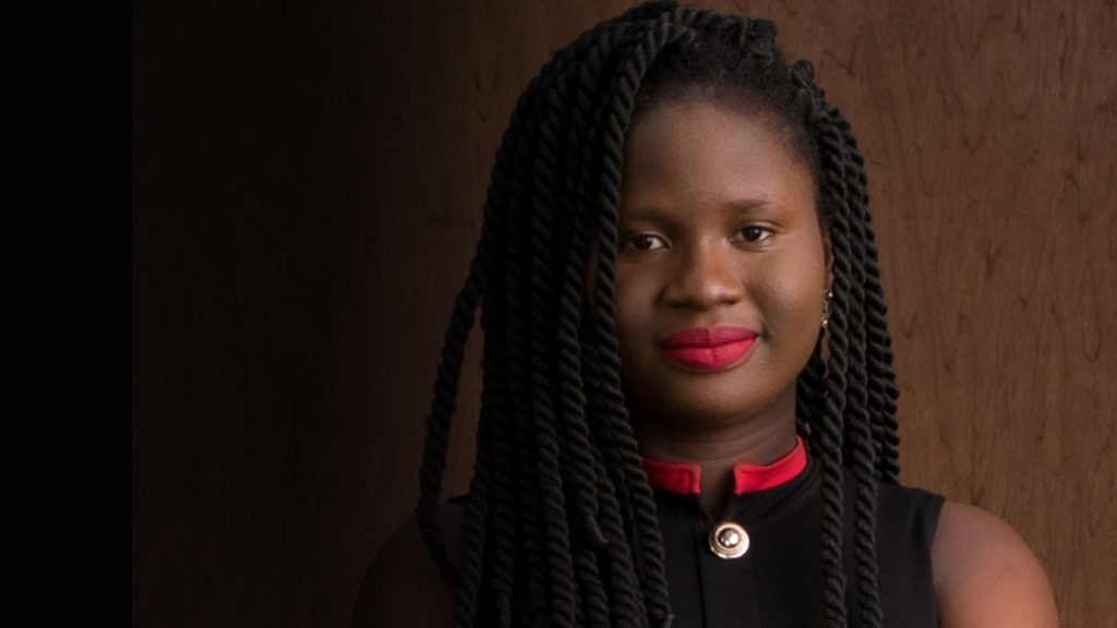 a young woman with dreadlocks posing for a photo.