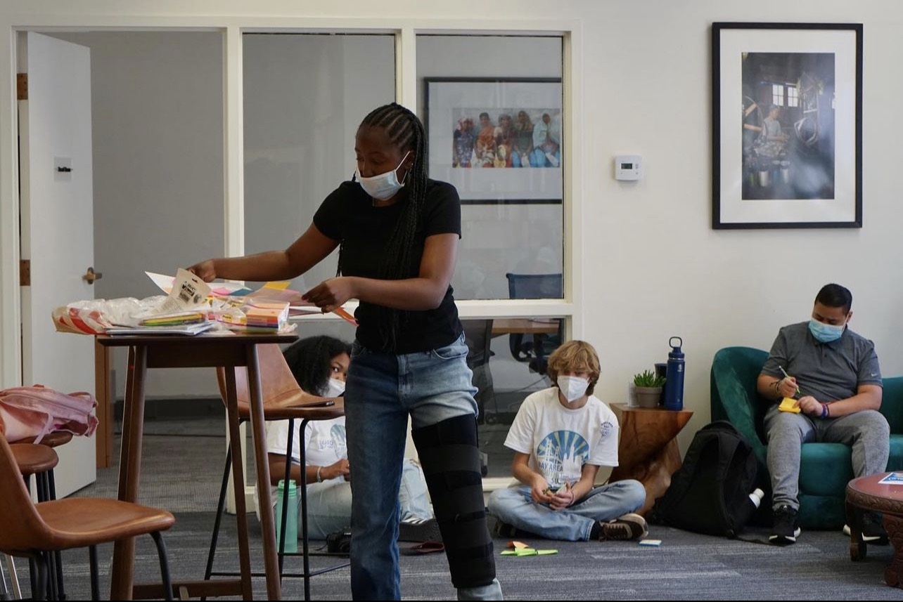 a woman wearing a face mask in a room with other people.