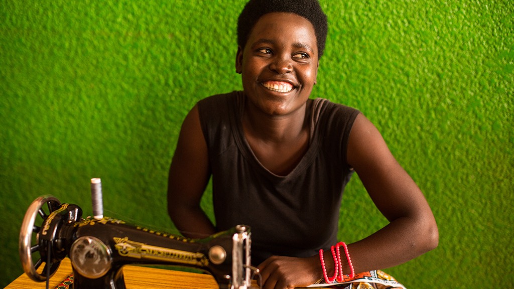 a woman smiling at a sewing machine.