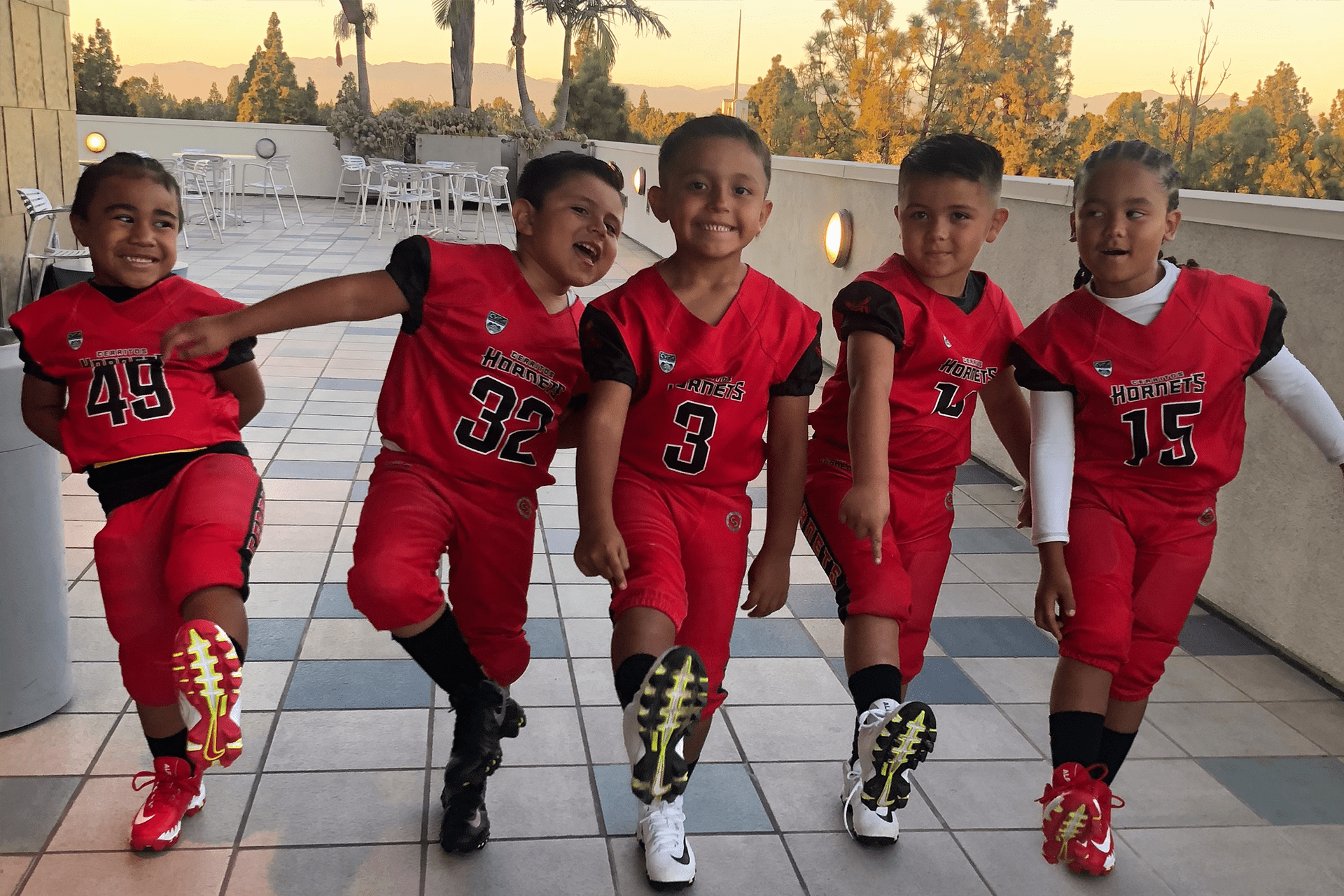 Youth football kids in red jersey showing off new football shoes