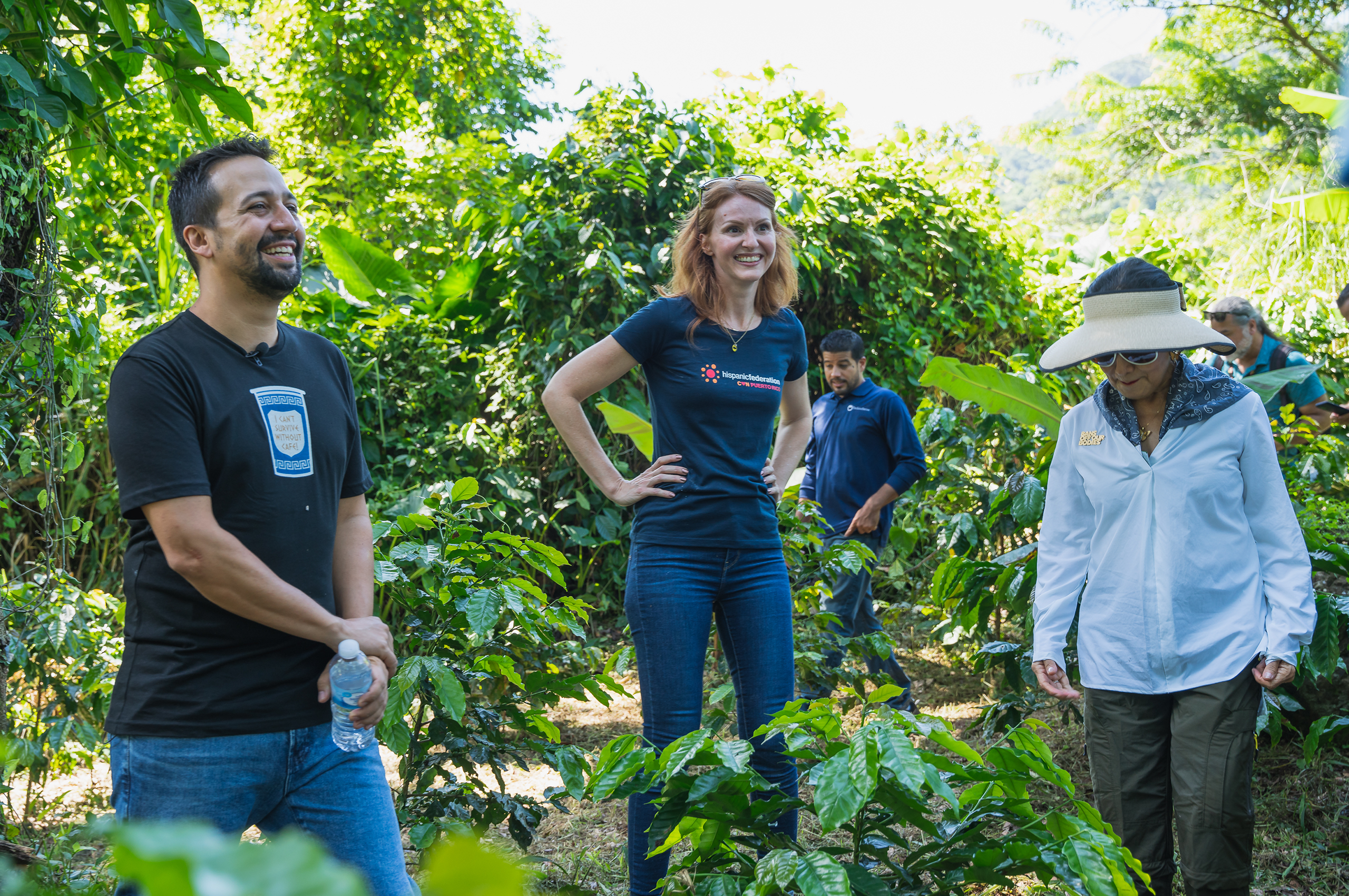 a group of people standing in a coffee plantation.