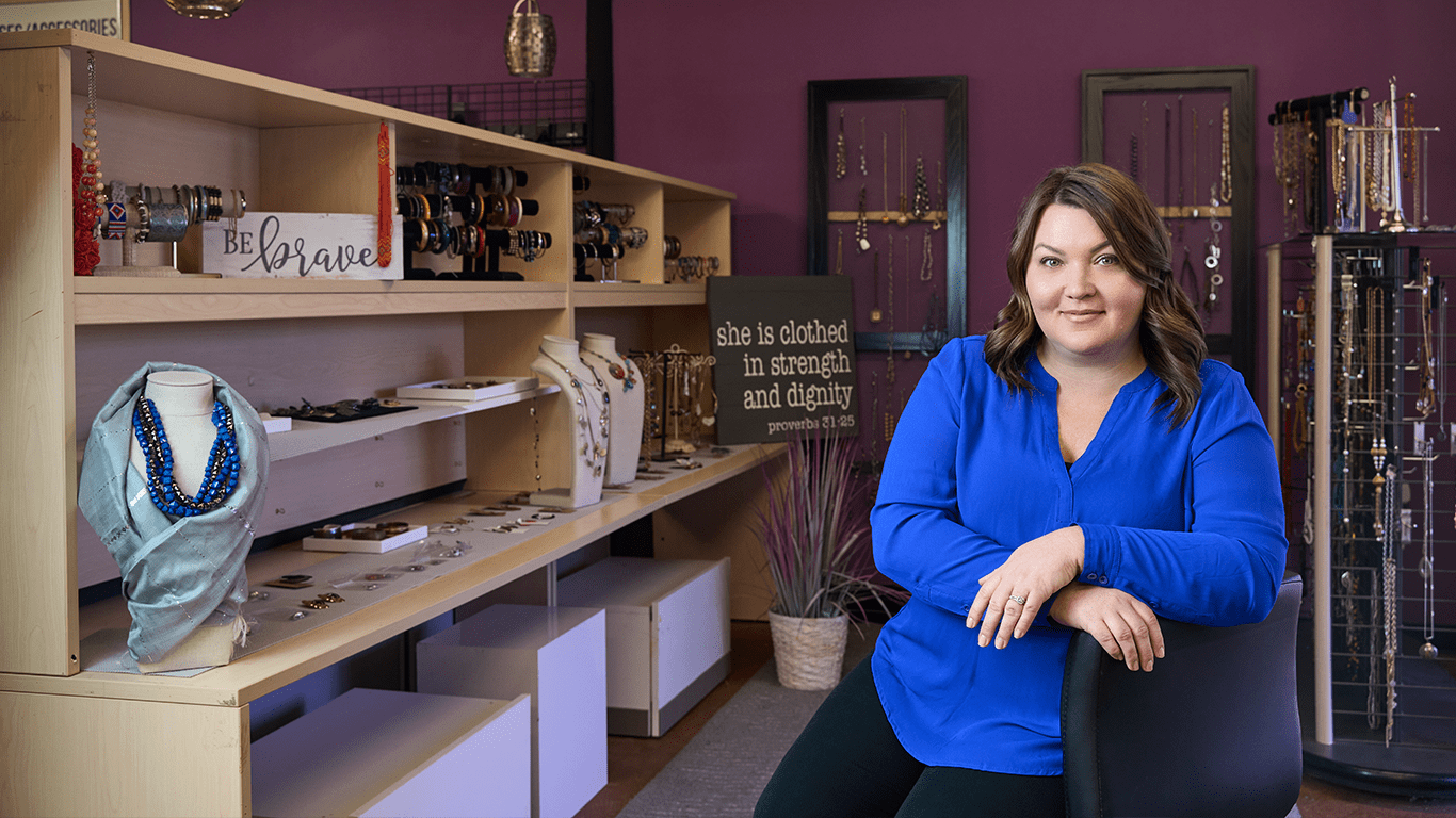 a woman sitting in front of a jewelry store.